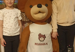 dzieci stiją przy misiu