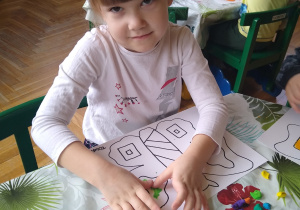 Dziewczynka wykleja plasteliną kontur motyla