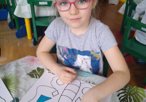 Dziewczynka wykleja plasteliną kontur motyla