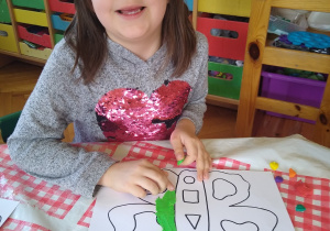 Dziewczynka wykleja plasteliną kontur motyla
