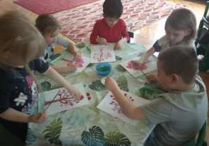 Dzieci przyklejają kulki z bibuły.