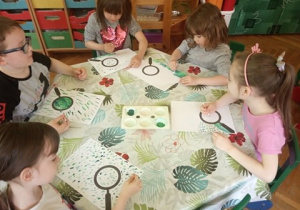 Dzieci wykonują pracę plastyczną o biedronkach.