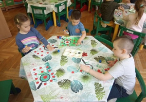 Dzieci wykonują pracę plastyczną o biedronkach.