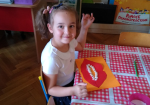 Dzieci wycinają usta z kartki, czerwonego papieru, naklejają fasolę