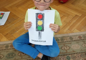 Chłopiec prezentuje swoją pracę plastyczną.