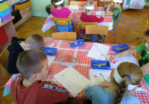 Dzieci rysują kredkami przy stolikach