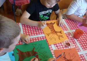 Dzieci malują farbami.