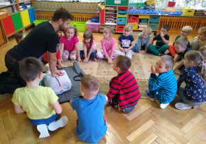 Dzieci obserwują strażaka demonstrującego na fantomie jak udzielać pierwszej pomocy