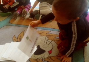 dzieci siedzą na dywanie i odkrywją kartki z warzywami