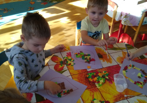 Dzieci wyklejają wydzieranką kontur liścia