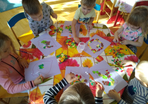 Dzieci wyklejają wydzieranką kontur liścia