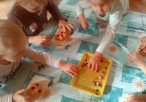 dzieci lepią z masy solnej bułki i rogale i ozdabiają je guziczkami