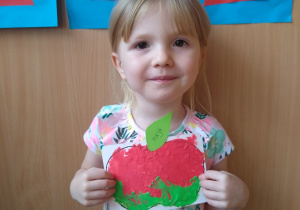 Dziewczynka prezentuje swoją pracę- wyklejone plasteliną jabłko