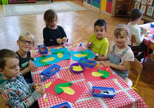 Dzieci przy stolikach naklejają kukurydzę z zielonego i żółtego papieru