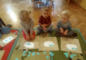 dzieci na dywanie układają kropelki wycięte z papieru kolorowego