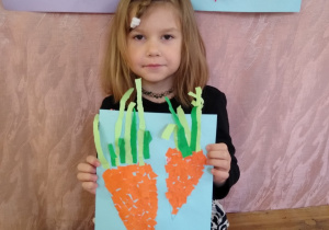 Dziewczynka prezentuje swoją pracę- marchewki z wydzieranki