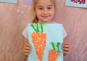 Dziewczynka prezentuje swoją pracę- marchewki z wydzieranki