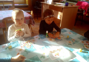 dzieci wyklejają kontury listków kolorowymi kółeczkami