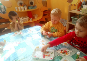 dzieci wyklejają kontury listków kolorowymi kółeczkami