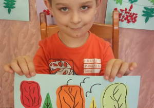 Chłopiec prezentuje swą pracę "Park jesienią".
