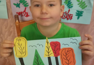 Chłopiec prezentuje swą pracę "Park jesienią".