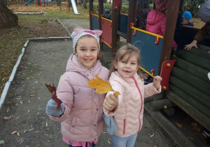 Dziewczynki pokazują jesienne liście.