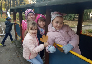 Dziewczynki bawią się w lokomotywie, w tle biegnie chłopiec.