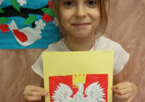 Dziewczynka prezentuje swą pracę "Godło Polski".