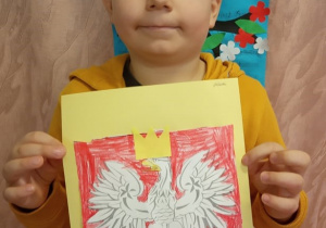 Chłopiec prezentuje swą pracę "Godło Polski".