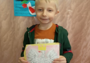 Chłopiec prezentuje swą pracę "Godło Polski".