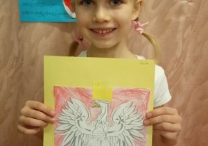 Dziewczynka prezentuje swą pracę "Godło Polski".