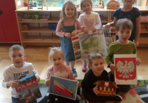 Dzieci prezentują symbole narodowe i książkę o Polsce.