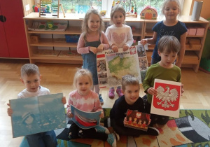 Dzieci prezentują symbole narodowe i książkę o Polsce.