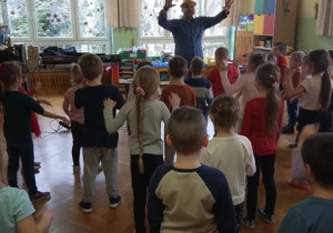 Dzieci śpiewają i tańczą razem z panem prowadzącym zabawy muzyczne.