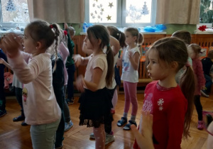 Dzieci patrzą na pana prowadzącego zabawy i naśladują jego ruchy.