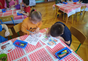 Dzieci wykonują karty pracy przy stoliku