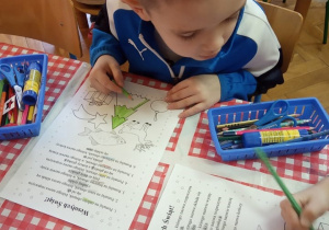 Chłopiec koloruje obrazki zgodnie z odczytywanym poleceniem.