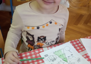 Dziewczynka koloruje obrazki zgodnie z odczytywanym poleceniem.