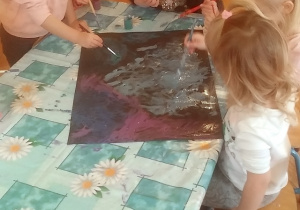 dzieci malują czarny karton farbami