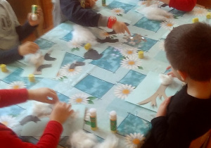 dzieci wyklejają ptaszki z papieru i śnieg z waty