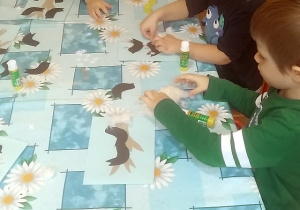dzieci wyklejają ptaszki z papieru i śnieg z waty