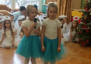 Dziewczynki zapraszają do występu "Choineczki" z III grupy.