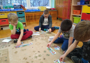 Dzieci na dywanie układają historyjkę obrazkową.