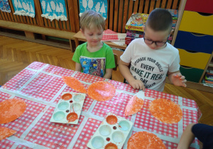 Dzieci pracują przy stolikach.