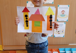 chłopiec prezentuje prace plastyczną - zamek z figur geometrycznych