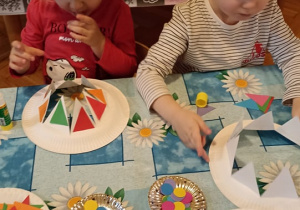 dzieci prezentują czpki karnawałowe wykonane z talerzyków papierowych