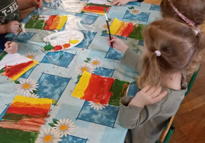 dzieci malują tło farbami
