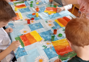 dzieci malują tło farbami