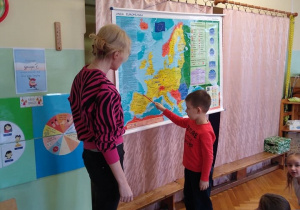 Chłopiec wskazuje na mapie Hiszpanię.
