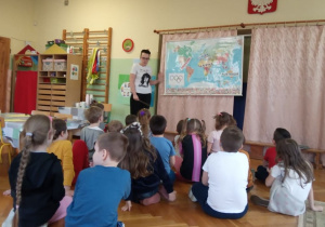 Dzieci wskazują na mapie świata kontynenty.